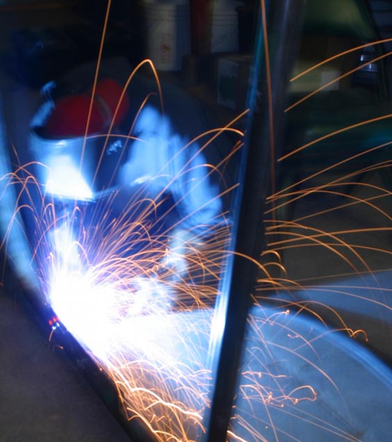 Welding with man in background and sparks in front